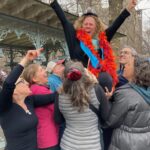 Devora Yellin Fish is being lifted up in the air by friends, family, and collogues.
