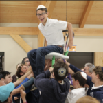 13 year old boy being uplifted by his friends in a personalized painted chair